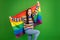 Portrait of attractive cheerful girl holding in hands lgbt flag having fun dancing isolated over bright green color