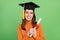 Portrait of attractive cheerful girl holding scroll paper finish get higher phd degree isolated over green color