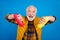 Portrait of attractive cheerful grey-haired man holding bottles ketchup adding dish meal isolated over bright blue color