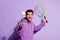 Portrait of attractive cheerful guy playing active tennis having fun isolated over purple violet color background