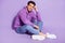 Portrait of attractive cheerful guy sitting resting spending weekend  over purple violet color background