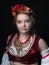 Portrait of attractive confident woman in traditional costume in ukranian national stile with circlet of flowers, red vest