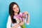 Portrait of attractive cute sweet girl holding flowers touching petals isolated over brigth blue color background