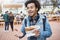 Portrait of attractive dark-skinned guy with afro hair gesturing while discussing something with friends, eating