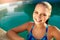 Portrait of attractive emotional blonde girl smiling in the pool side. Young teen wet woman with burning eyes came out