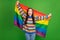 Portrait of attractive excited cheerful girl holding in hands lgbt flag having fun isolated over bright green color