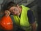 Portrait of attractive and exhausted construction worker in helmet and vest at building site taking a breath during a hard working