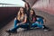 Portrait of an attractive family. Mother and her daughters sitting together on a skateboard at bridge footway.