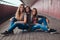 Portrait of an attractive family. Mother and her daughters sitting together on a skateboard at bridge footway.