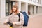 Portrait of attractive female courier with big thermo backpack standing with electric scooter in city street.