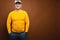 Portrait of an attractive friendly Caucasian man in a cap and yellow sweater on a brown background. Nice middle aged guy