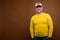 Portrait of an attractive friendly Caucasian man in a cap and yellow sweater on a brown background. Nice middle aged guy