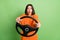 Portrait of attractive funny amazed girl holding steering wheel driving fast speed rental isolated over bright green