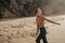 Portrait of attractive girl with light brown hair running on rocky Ursa beach on sunset. Smiling looking to the camera