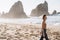 Portrait of attractive girl with light brown hair walking on rocky Ursa beach on sunset. back view