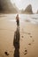 Portrait of attractive girl and long shadow on sand walking on rocky Ursa beach on sunset. back view