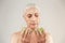 Portrait of an attractive half naked elderly woman looking at two slices of green apple isolated over white background