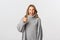 Portrait of attractive happy woman in grey sweater, encourage you, showing thumb-up in approval and winking, recommend