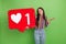 Portrait of attractive indifferent girl holding in hands big large like board isolated over bright green color