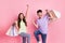 Portrait of attractive lucky cheerful couple carrying news clothes having fun best black friday isolated on pink pastel