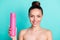 Portrait of attractive naked nude cheerful girl holding in hand pink bottle spray  over bright teal turquoise
