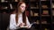 Portrait of attractive red-haired young woman journalist interviewing person in cozy dark room.