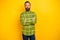 Portrait of attractive serious man it expert wearing checked shirt folded arms isolated over bright yellow color