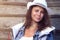 Portrait of attractive tanned young woman in cowboy hat against wooden fence in denim jacket. Beautiful girl in hat