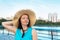 Portrait of attractive traveling mature woman in straw hat spending her leisure time on the embankment. Summer mood. Lifestyle