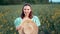 Portrait of attractive woman posing in blooming canola flowers field. Elegant girl in retro dress with straw hat