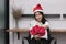 Portrait of attractive young Asian woman in Santa hats holding a bouquet of red roses in office.