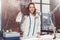 Portrait of attractive young Caucasian brunette dressmaker standing in white clothes holding steam iron in studio.