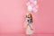 Portrait of attractive young woman holding cute little birthday girl with party balloons in her arms. Fascinating curly