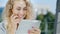 Portrait of an attractive young woman uses tablet on a summer area in the cafe. Smiles, positive emotions