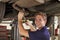 Portrait Of Auto Mechanic Working Underneath Car In Garage