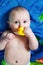 Portrait of baby boy holding yellow rubber duck in mouth after bathing