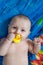 Portrait of baby boy holding yellow rubber duck in mouth after bathing