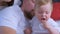 Portrait of baby is feeding parents mom and dad grapes at home.