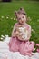 portrait baby girl in a pink dress plays with a rabbit in a green meadow in summer. Funny friendship between a child and