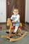 Portrait of baby girl playing on wooden rocking horse. Childhood, game at home concept