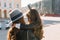 Portrait from back of brown-haired woman in felt hat holding on hands curly brunette daughter, enjoying city views