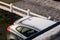 A portrait of the back of a grey car in a driveway with snow and ice on its roof and windows. The frozen parts are already melting