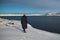 Portrait from back of warmly dressed woman in defocus standing in front of sea looking far away looking at winter rough