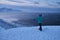 Portrait from back of warmly dressed woman in defocus standing in front of sea looking far away looking at winter rough