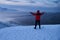 Portrait from back of warmly dressed woman in defocus standing in front of sea looking far away looking at winter rough