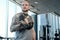 Portrait of a bald athletic man with a tattoo on his hand doing exercise with dumbbell in the modern fitness club