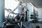 Portrait of a bald athletic man with a tattoo on his hand standing next to a exercise bike in the modern fitness club