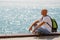 Portrait bald man on background sea. Tourist guy sitting on embankment near