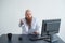 Portrait of a bald man at a desk looking at a report and cursing. The dissatisfied boss dismisses the subordinate.