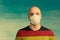 Portrait of a bald man in a respirator and and and a t-shirt with a picture of the German flag on a greenish background.